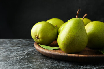 Wooden tray with green pears on black smokey background