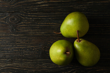 Fresh green pears on wooden background, space for text