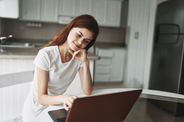 Woman at home in front of laptop sitting at the table working office 