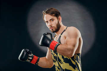 Naklejka na ściany i meble A man in Boxing gloves. A man Boxing on a black background. The concept of a healthy lifestyle