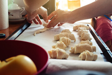 Close-up of a woman's hands sticking homemade cookies into the oven. Making sugar rolls from raw dough. Home cooking, quarantine and self-isolation concept.