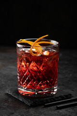 Classic old fashioned Cocktail in a retro glass with ice and orange peel on a black background