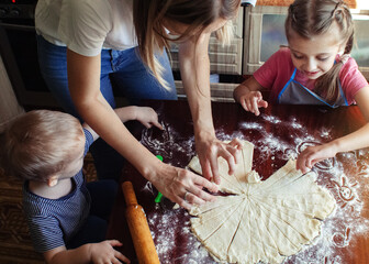 Mom and children prepare dough in the kitchen during self-isolation and quarantine. Hands of a...