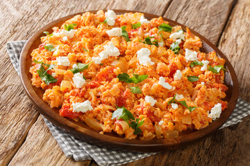 Greek scrambled eggs with fresh tomatoes, onions and feta cheese close-up in a plate on the table. horizontal