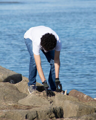 person on the rocks picking up trash