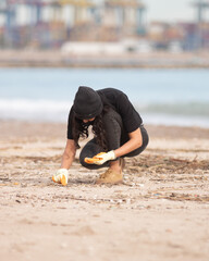 child picking up trash on the beach