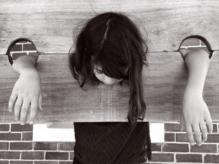 Sad young girl in a pillory