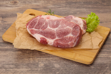 Raw pork steak over wooden board