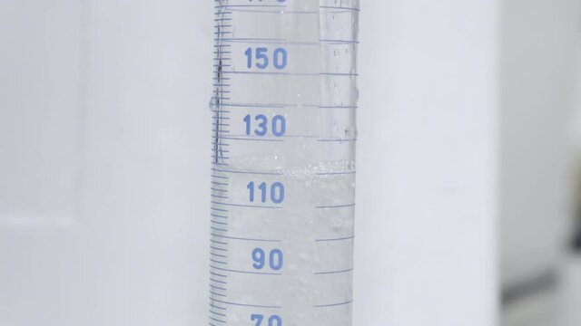 Filling of measuring cylinder. Cylindrical lab glassware showing measurement of liquid level on a scale. 