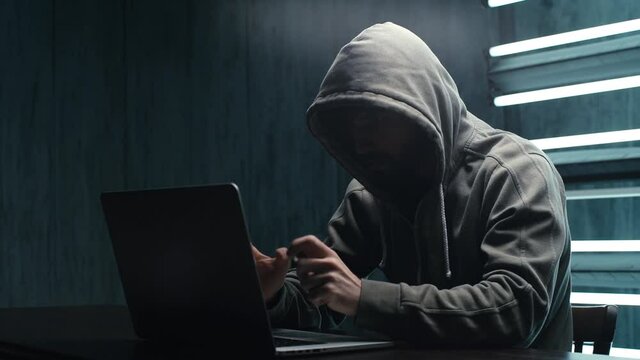 Unrecognizable hacker man stretching hands and starting to typing on laptop keyboard and breaking password. Male engaging hacking into security systems. Freelancer using laptop working from home.