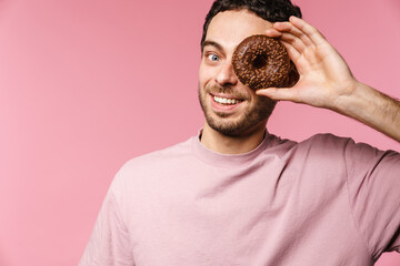 Joyful handsome guy smiling while making fun with doughnut