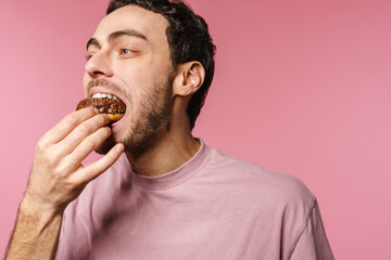 Joyful handsome hungry guy eating doughnut on camera