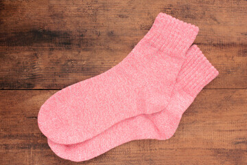 Pair of pink knitted socks on wooden background. Overhead view. Copy space
