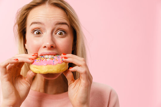 Excited charming hungry girl eating doughnut on camera