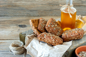 Closeup of multigrain or whole grain bread rolls with oil bottle in a cloth lined in wooden box.