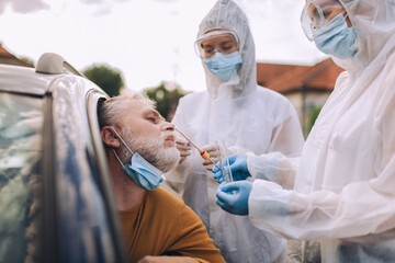 Doctors in a protective suit taking swab from a person to test for possible coronavirus infection