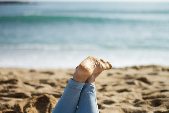 Girl On The Beach With Bare Feet Up On The Sea Bottom