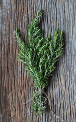 fresh ecological rosemary bouquet tied with a rope and on an old wooden plank