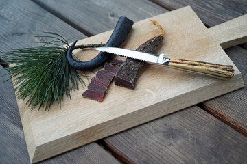 delicious ham of a chamois buck on the wood board with a hunting knife and a twig from the swiss stone pine