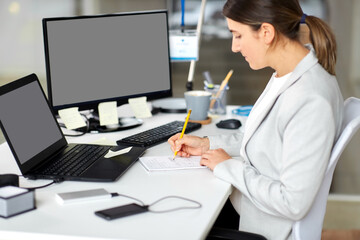 business, technology and people concept - businesswoman with notebook and laptop computer working at office