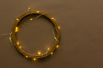 Top view of wooden ring and golden shiny garland on the brown surface.Empty space