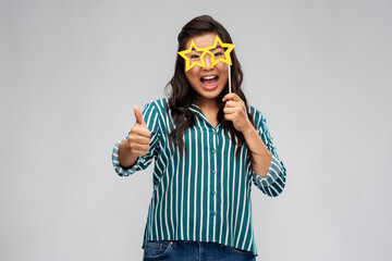 party props, photo booth and people concept - happy asian young woman with big glasses in shape of stars showing thumbs up over grey background