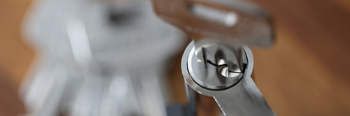 Steel key in keyhole lying on wooden table closeup. Reliable property protection concept. © H_Ko