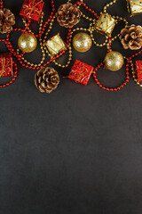 Christmas decorations in gold and red on a black background with free space. View from above.