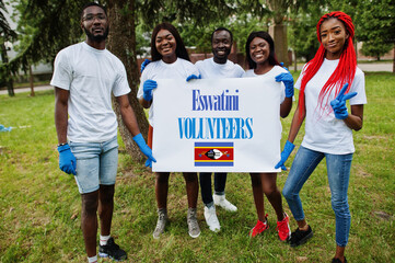 Group of happy african volunteers hold blank with Eswatini flag in park. Africa countries volunteering, charity, people and ecology concept.