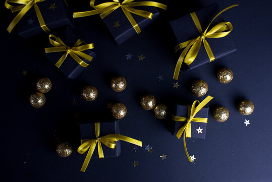 Black gifts with gold ribbons and gold christmas balls and stars.Set of gift box isolated on black background.Christmas gift boxes on black background.Merry Christmas and Happy Holidays greeting card.