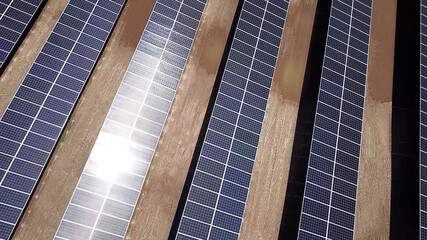 Reflection of sunlight on solar power panels in the desert. aerial top above view of photovoltaic PV modules in solar energy plant farm background