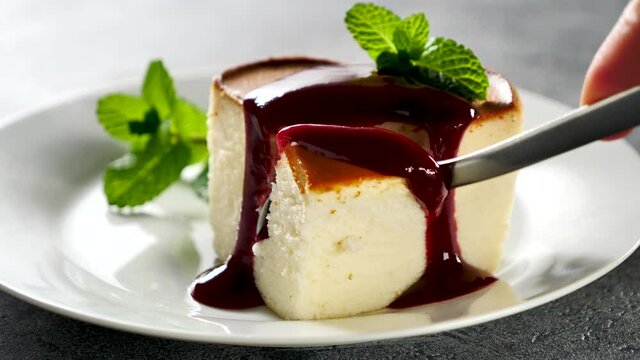 eating cheesecake and berry fruit sauce