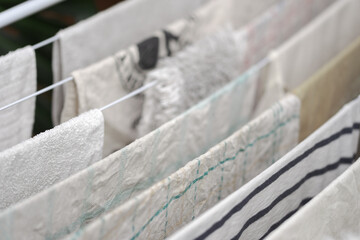 Detail of dish towels and other white laundry hanging on clothes horse to dry