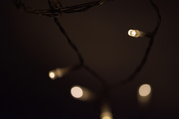 Chain of LED fairy lights hanging from cupboard on white wall for indoor christmas decoration