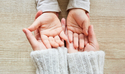 Hände von einem Kleinkind in Händen der Mutter