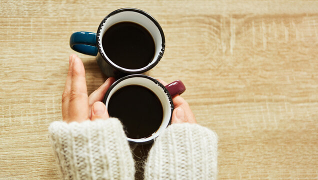 H&auml;nde w&auml;rmen sich an einem Becher Kaffee