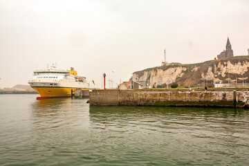 Obraz premium Dieppe. Ferry à quai dans le port et église Notre-Dame de Bon-Secours sous ciel de brume. Seine-Maritime. Normandie