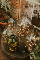 Fototapeta premium Light decorations in big wine bottles. Wedding decor. christmas decoration. Botanical style. 