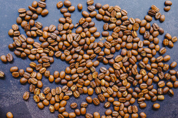 Roasted coffee beans spread on a black background