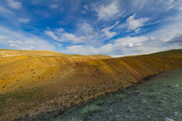 Panoramic view of a mountain. Altai mountains. Blue sky, white clouds.