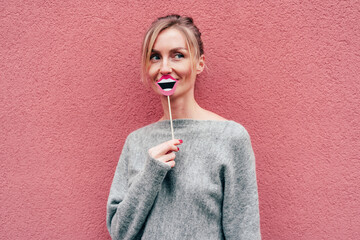 Beautiful elegant stylish blonde on a pink background with a paper smile. Joky lifestyle portrait....