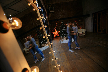 lovers in gray sweaters and jeans on the background of the Christmas tree