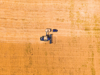 Aerial view of combine harvester on wheat field.