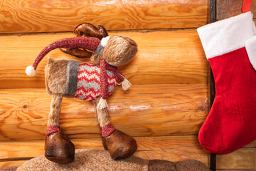 Fototapeta na wymiar New Year's still life of four red New Year sock for gifts, toy in the form of a plush christmas deer on the background of a wooden wall in a country house