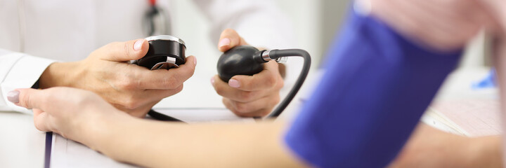 Doctor cardiologist measuring blood pressure of patient with tonometer in clinic. Diagnostics and treatment of diseases of cardiovascular system concept