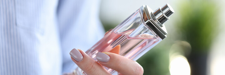 Fototapeta na wymiar Woman holding bottle of perfume in her hands closeup. Aromatherapy concept