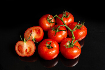 several large tomatoes with water drops on a black background