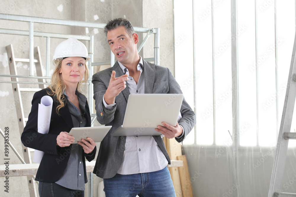 Wall mural man and woman architects or engineers with computer work together in the inside the construction building site