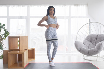 Woman during her fitness workout at home with rubber resistance band.