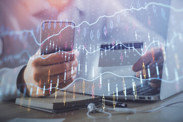 Double exposure of man hands holding a credit card and Forex graph drawing. Stock trading and digital fintech in Internet E-commerce concept.